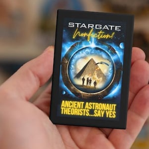 May include: A black and yellow button with the text "Stargate Nonfiction!" and "Ancient Astronaut Theorists...Say Yes". The button features a blue and black image of a pyramid with a ring around it.