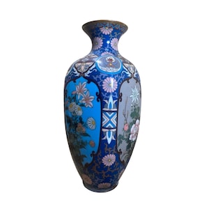 Pode incluir: Um vaso cloisonné alto e esguio com um fundo azul vibrante decorado com padrões florais intrincados, incluindo crisântemos e lírios cor-de-rosa. A superfície apresenta painéis detalhados com motivos botânicos e bordas geométricas.