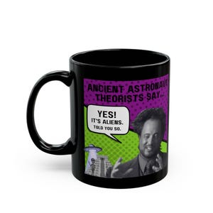 May include: Black coffee mug with a graphic of a man with a speech bubble that says "YES! It's aliens. Told you so." The graphic is in a comic book style with a purple and green background. The text on the mug reads "Ancient Astronaut Theorists Say..."