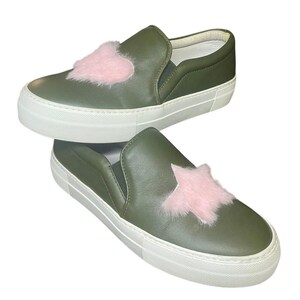 May include: Olive green slip-on sneakers with white soles. One shoe features a pink heart, the other a pink star, both made of fluffy material. The shoes have a minimalist design.