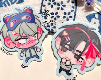 May include: Two anime-style stickers with light blue outlines. One features a character with gray hair and a sleep mask, the other with black hair and pink accents. The text "IVANTILL" is visible on one sticker.