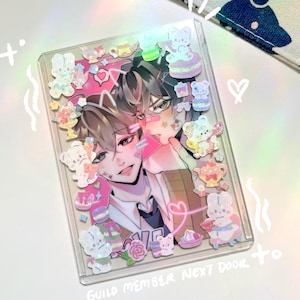 May include: Clear plastic card holder with an anime-style illustration of two male figures. The card is decorated with pastel-coloured bear and dessert-themed stickers. Text at the bottom reads "Guild Member Next Door to".