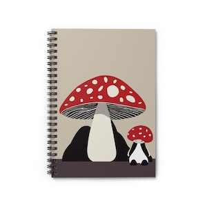 Può includere: Quaderno a spirale con un'illustrazione di funghi. Il design presenta un grande fungo con cappello rosso e pois bianchi, un gambo color crema e un fungo più piccolo con cappello rosso e corpo bianco e nero. Sfondo beige neutro.