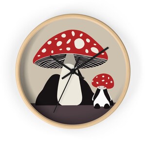 Puede incluir: Un reloj de pared redondo con un fondo beige que presenta dos setas rojas y blancas con manchas negras. La seta más grande tiene un tallo blanco y un sombrero a rayas blanco y negro. La seta más pequeña tiene un tallo blanco y un sombrero rojo. Las manecillas del reloj son negras.