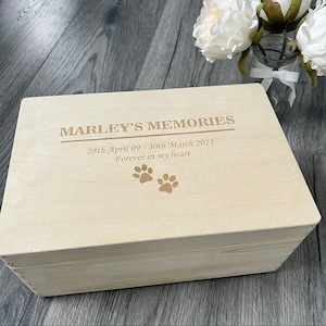 May include: A wooden box with a lid, engraved with the text "Marley's Memories", "28th April 09 - 30th March 2021", and "Forever in my heart". Two paw prints are also engraved on the lid.
