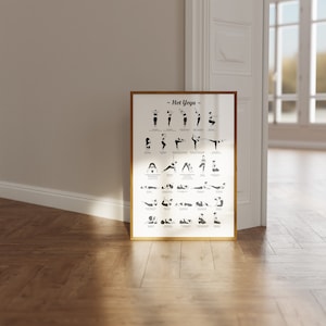May include: A black and white poster with the title "Hot Yoga" and illustrations of different yoga poses. The poster is framed in a gold frame and is hanging on a white wall.