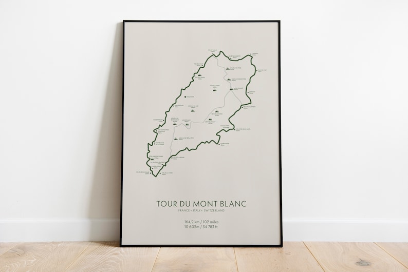 Może przedstawiać: Czarny plakat w ramie z mapą szlaku Tour du Mont Blanc. Mapa pokazuje trasę szlaku przez Francję, Włochy i Szwajcarię. Plakat zawiera tekst "Tour du Mont Blanc", "Francja - Włochy - Szwajcaria", "164,2 km / 102 mile", i "10 620m / 34 783 ft".