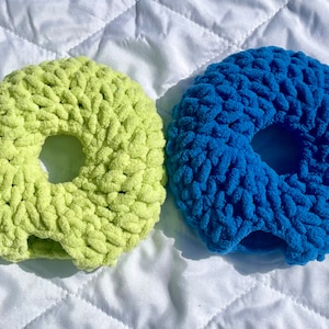 May include: Two crocheted donut-shaped rings, one in a light green color and the other in a bright blue color.