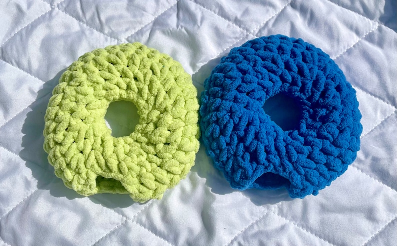 May include: Two crocheted donut-shaped rings, one in a light green color and the other in a bright blue color.