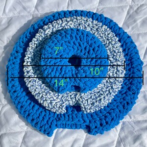 May include: A blue and white crocheted ring with three layers. The inner ring measures 7 inches in diameter, the middle ring measures 10 inches in diameter, and the outer ring measures 14 inches in diameter.