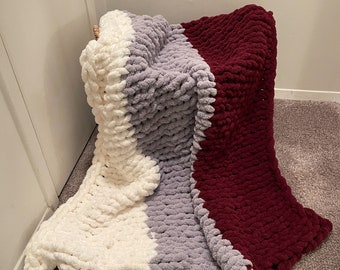 May include: A chunky knit throw blanket with three horizontal stripes in white, gray, and burgundy.