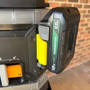 May include: Close-up of a black and gray power tool with a black 18V Li-ion 2.0Ah battery attached. The battery has green and white text. A yellow release lever is visible.
