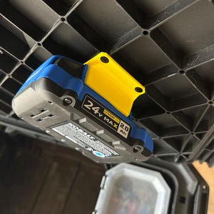 May include: A blue and black 24V MAX 2.0 Ah Lithium Ion battery with a yellow bracket attached. The battery is mounted to a black plastic storage container. The battery has the brand name "KOBALT" printed on it.