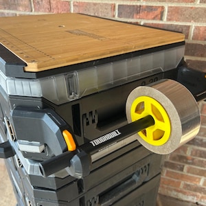 May include: A black and gray Toughbuilt rolling tool box with a bamboo top and a silver and yellow ab wheel. The tool box has a handle and orange accents. The ab wheel has the word "TOUGHBUILT" printed on it.