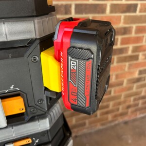 May include: A black and red Craftsman V20 4.0 Ah Lithium Ion battery pack attached to a black and gray tool. The battery pack has white text and a red and black label. The tool has yellow and orange accents.