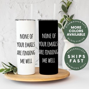 May include: Two stainless steel tumblers with a black and white design. The tumblers have the text "None of your emails are finding me well" printed on them. The tumblers are on a wooden coaster. The background is a white brick wall.