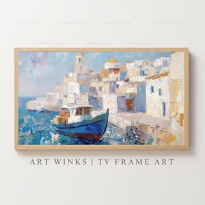 以下が含まれることがあります： 青いボートを前景にした、海岸沿いの村の油絵。このアートワークは、白い建物、教会、港を特徴としています。絵画は明るい木製のフレームに額装されています。「ART WINKS | TV FRAME ART」というテキストが下にあります。