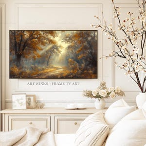 May include: A framed landscape art piece depicting a forest scene with golden-hued trees and sunlight streaming through the branches. The artwork is displayed above a white cabinet, with decorative elements like flowers and pillows.