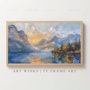 May include: A framed landscape oil painting depicts a mountain range reflected in a lake. The artwork features a palette of blues, yellows, and oranges, with visible brushstrokes. The text "ART WINKS | TV FRAME ART" is at the bottom.