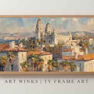 May include: Oil painting of a cityscape with a large white building with gold domes, surrounded by smaller buildings with orange tile roofs. The artwork is framed in a light wood frame. Text at the bottom reads "ART WINKS | TV FRAME ART."