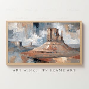 May include: An abstract landscape painting of a desert scene with a large mesa in the center, framed in a light wood. The artwork features a palette of muted oranges, browns, and blues, with the text "ART WINKS | TV FRAME ART" at the bottom.