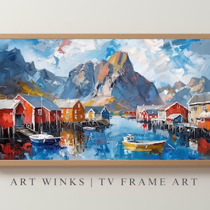 May include: Oil painting of a coastal village with red and orange buildings on stilts, set against a backdrop of mountains and a blue sky. Small boats float in the water. The artwork is framed in a light brown wooden frame. Text at the bottom reads "ART WINKS | TV FRAME ART".