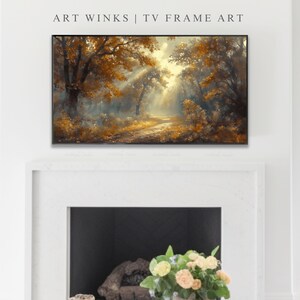 May include: A framed art piece with a landscape painting of a forest scene. The artwork features a path leading through trees with golden and brown leaves, illuminated by sunlight. The text "ART WINKS | TV FRAME ART" is at the top.