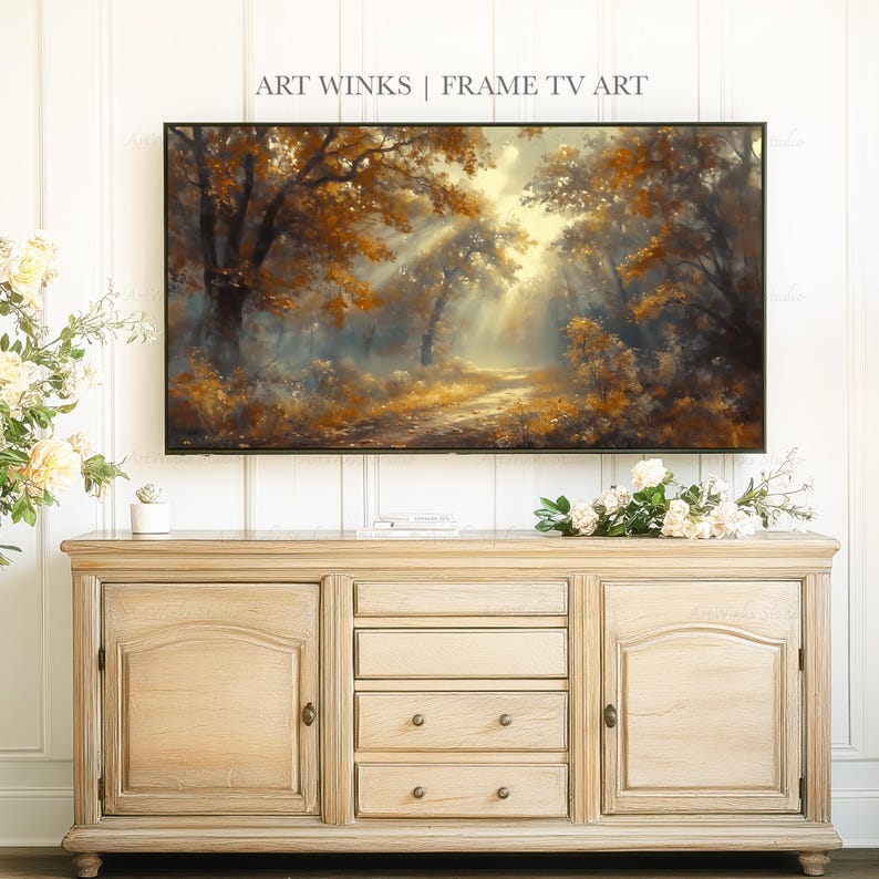 May include: A framed digital art print displays a forest scene with sunlight streaming through the trees. The artwork is above a light-colored wooden cabinet with doors and drawers. The text "ART WINKS | FRAME TV ART" is at the top.