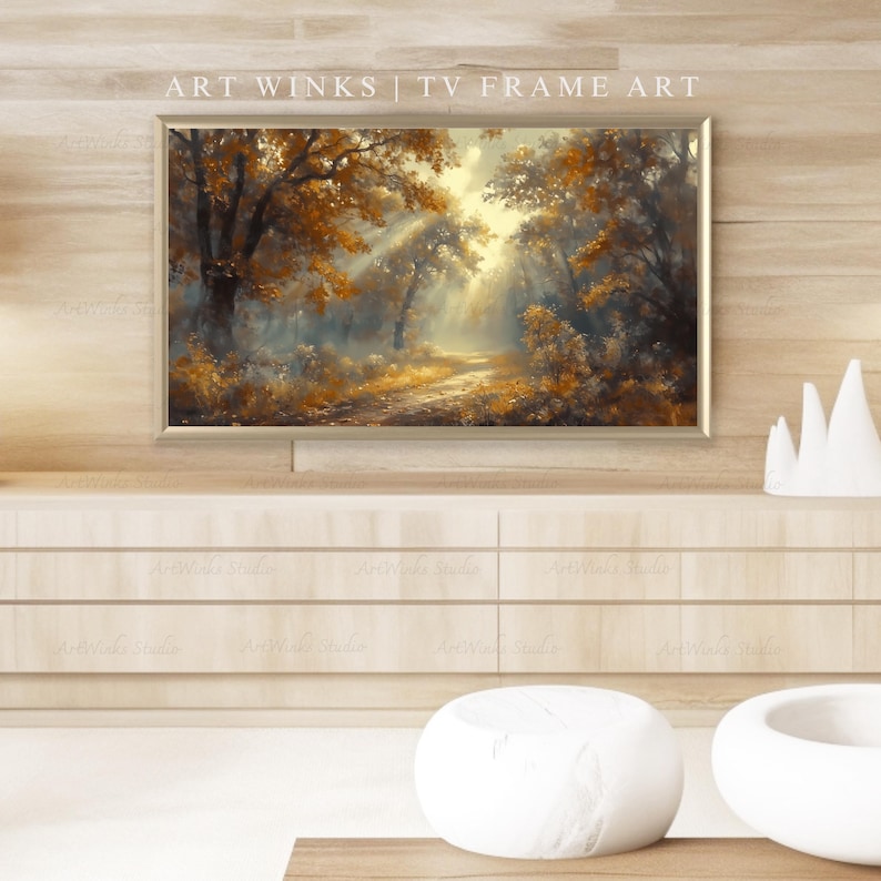 May include: A framed landscape painting depicting a forest scene with a path leading into the distance. The artwork features warm tones of gold, brown, and orange, with sunlight streaming through the trees. The text "ART WINKS | TV FRAME ART" is visible.