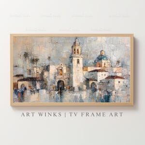 May include: An abstract painting of a cityscape with a light wood frame. The artwork features a church with a bell tower and a blue dome, rendered in shades of white, beige, and blue. The text "ART WINKS | TV FRAME ART" is at the bottom.