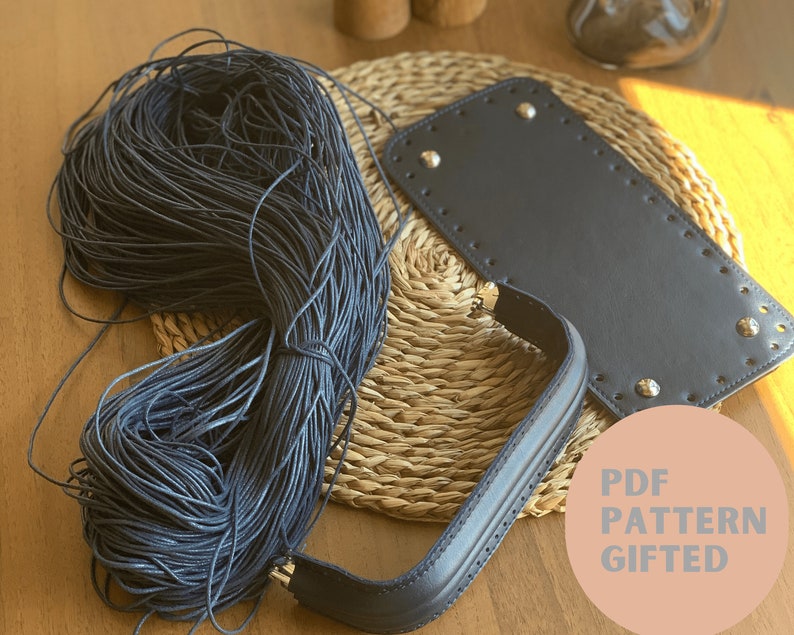 May include: A close-up of a dark blue cord, a black leather handle, and a black leather panel with silver rivets. The text "PDF PATTERN GIFTED" is on a pink circle.
