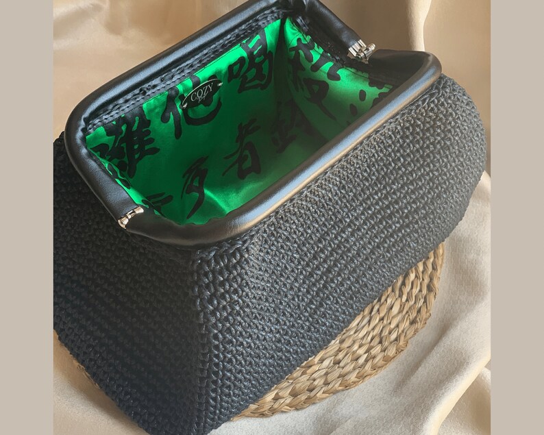 May include: A black crocheted clutch purse with a green satin lining. The lining features black Chinese characters and the word "Cozy" in white.