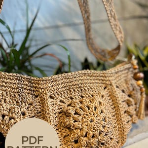 May include: A crocheted bag with a brown strap and a floral design. The bag is made with a natural fibre and has a rustic look. The image includes the text "PDF PATTERN".