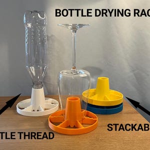 Puede incluir: Un escurridor de botellas de plástico transparente con una base blanca, una rosca de botella naranja y componentes de secado apilables amarillos y azules. El texto "BOTTLE DRYING RACK", "BOTTLE THREAD" y "STACKABLE" es visible.