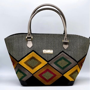 May include: A black and white chevron patterned tote bag with a geometric design of colorful embroidered diamonds. The bag has two brown leather handles.