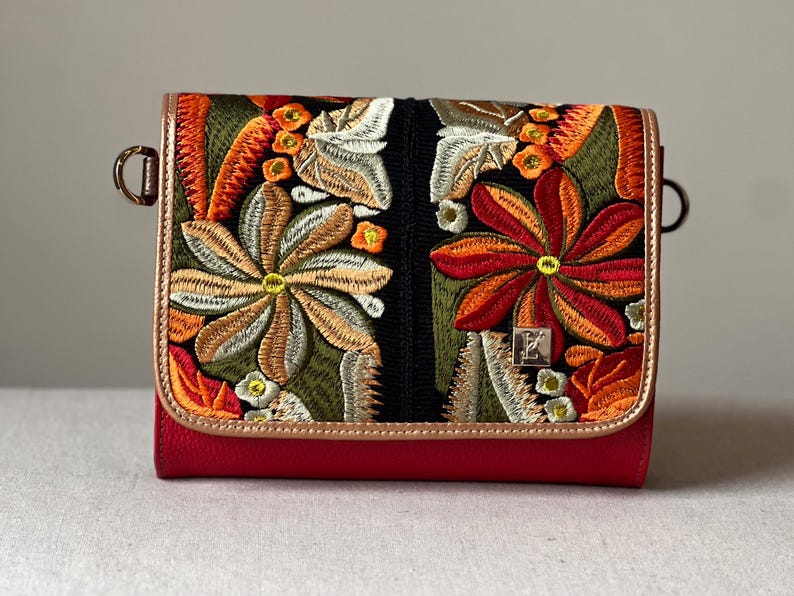 May include: A red leather crossbody bag with an embroidered floral design on the flap. The embroidery features orange, green, and white flowers. The bag has gold-tone metal trim and hardware.