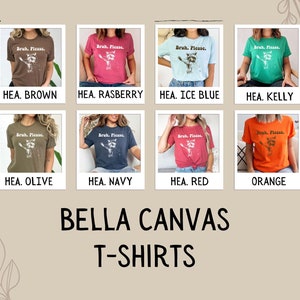 May include: A set of ten Bella Canvas t-shirts in various colours, featuring a graphic of a raccoon with the text "Bruh. Please." printed on the front. The colours include brown, raspberry, ice blue, kelly green, olive, navy, red, and orange.