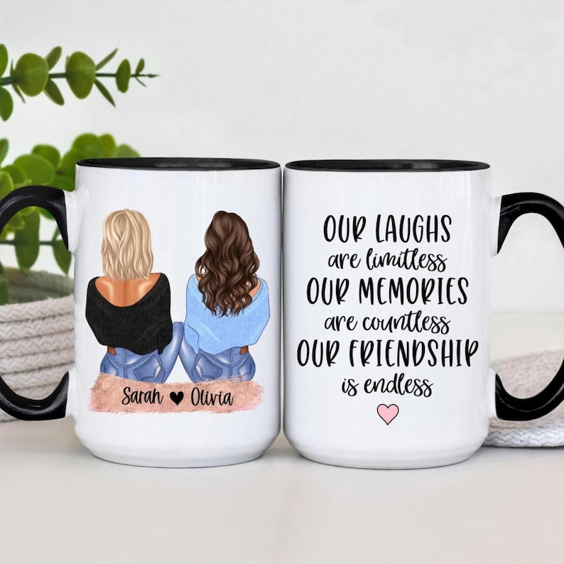 May include: Two white ceramic mugs with black handles and rims. One mug features an illustration of two friends and the names "Sarah" and "Olivia." The other mug has the text "Our laughs are limitless, our memories are countless, our friendship is endless."