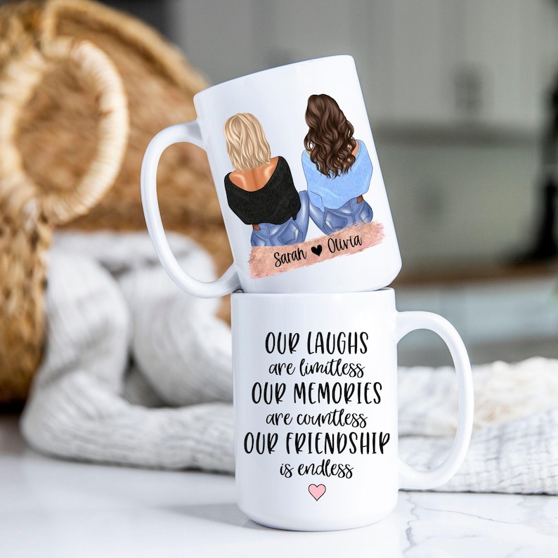 May include: Two white ceramic mugs stacked. The top mug features an illustration of two friends with the names "Sarah" and "Olivia." The bottom mug has the text "Our Laughs are limitless, Our Memories are countless, Our Friendship is endless."