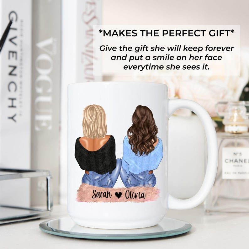 May include: White ceramic mug featuring illustrations of two women with blonde and brown hair, wearing black and blue tops and jeans. The mug has the names "Sarah" and "Olivia" printed on it. The mug is on a mirrored coaster.