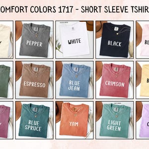 May include: A grid of fifteen Comfort Colors 1717 short sleeve t-shirts in various colors including ivory, pepper, white, black, blossom, moss, espresso, blue jean, crimson, butter, berry, blue spruce, yam, light green, and orchid.