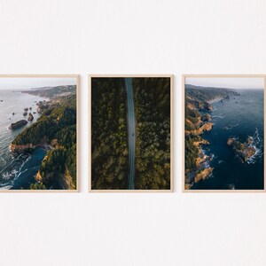 May include: Three framed photographs of a coastal landscape. The left photo shows a rocky coastline with green trees and a blue ocean. The middle photo shows a road winding through a forest. The right photo shows a rocky coastline with a blue ocean.