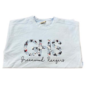 May include: Light blue sweatshirt with a floral embroidered "GHS Greenwood Rangers" design.