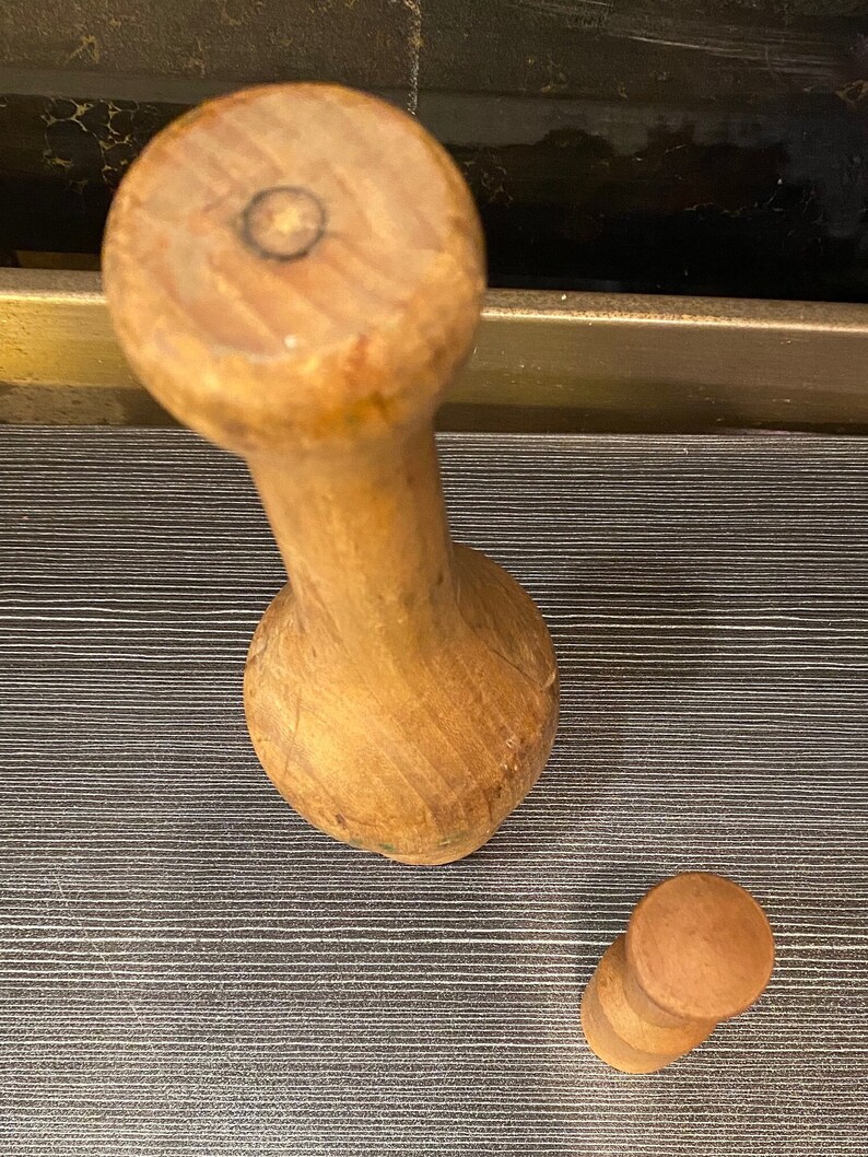 Peut inclure: Un ensemble de mortier et pilon en bois. Le mortier est de couleur brun clair avec une base arrondie et une longue poign&eacute;e cylindrique. Le pilon est une pi&egrave;ce cylindrique plus petite avec un dessus arrondi. L'ensemble est en bois.
