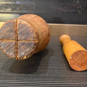 Peut inclure: Un ensemble de mortier et pilon en bois. Le mortier est de forme cylindrique avec une base en croix. Le pilon est une petite poign&eacute;e arrondie avec une base plate. Les deux pi&egrave;ces sont en bois brun clair.