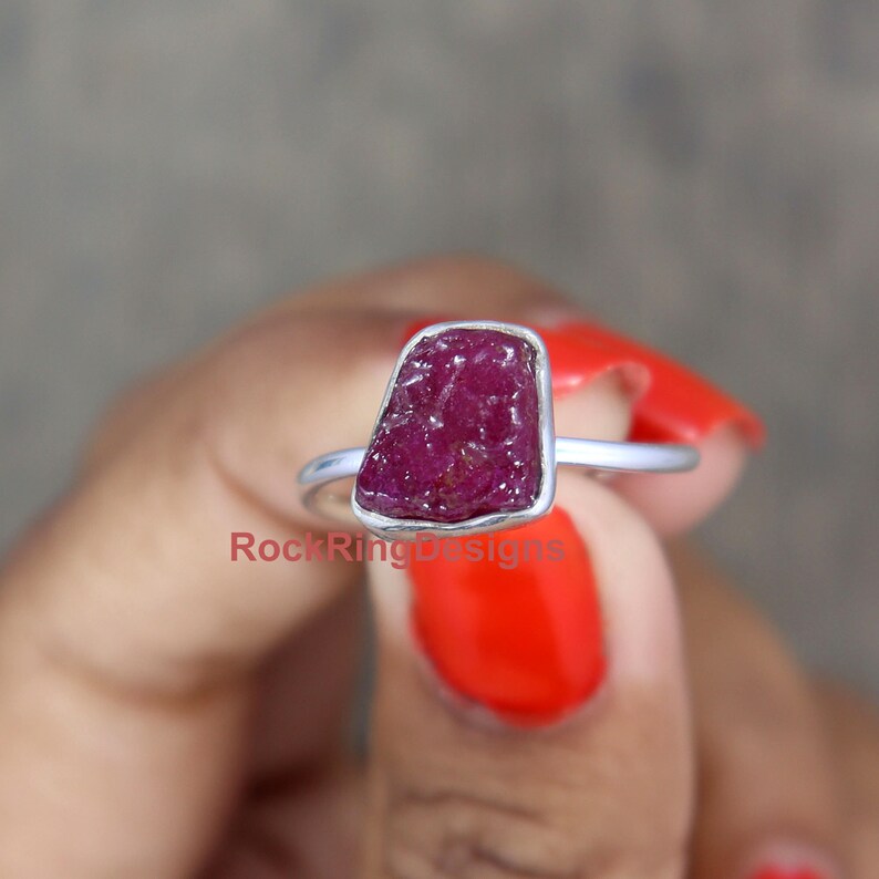 K&ouml;nnte beinhalten: Ein Silberring mit einem rohen Rubinstein. Der Rubin ist tiefrot und hat eine raue, nat&uuml;rliche Textur. Der Ring ist schlicht und elegant.