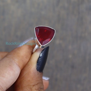Puede incluir: Un anillo de plata con una piedra roja triangular.