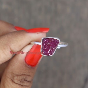 K&ouml;nnte beinhalten: Ein Silberring mit einem rohen, rosafarbenen Rubin-Edelstein. Der Rubin hat eine unregelm&auml;&szlig;ige Form und eine tiefe, satte Farbe.