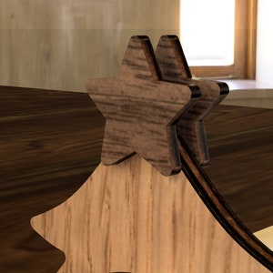 May include: Wooden Christmas tree ornament with two layered star shapes on top. The star shapes are made of dark wood and have a natural wood grain.