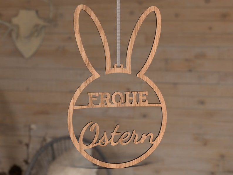 Może przedstawiać: Drewniana ozdoba wielkanocna w kształcie kr&oacute;lika z napisem "Frohe Ostern" w k&oacute;łku.